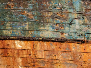 Paslı, turuncu ve mavi tonlarda ahşap pul pul dökülüyor. Yıpranmış doku zengin yüzey detaylarına sahip, ideal bir rustik arkaplan veya soyut arkaplan olarak.