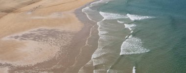 Fransa 'nın Brittany, Crozon yarımadasındaki Pen Hat plajında kumları yıkayan dalgalar. Doğal dokuları ve kıyı ışıklarıyla bomboş deniz kıyıları.