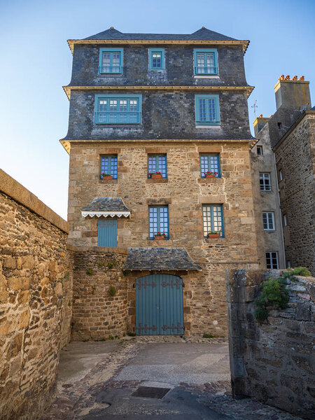 Сен-Мало, Франция, 17 мая 2025 года: традиционный каменный игрушечный дом с шиферной крышей и синими ставнями в историческом городе, классический бретонский архитектурный стиль.