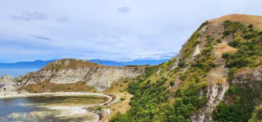 Kaikoura, Yeni Zelanda - 25 Ocak 2025: Yeni Zelanda 'da huzurlu bir kıyı sahnesi, batan güneşin altın renginin okyanusları yansıttığı yumuşak dalgalar.