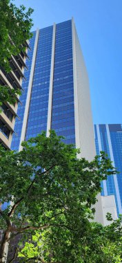 Sydney, Avustralya - 22 Ekim 2023: Parlak Cam Cepheli Modern High-Rise Binası. Çağdaş bir gökdelenin çarpıcı görüntüsü. Mavi gökyüzünü yansıtan parlak cam bir cephe.. 
