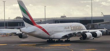 Auckland Uluslararası Havalimanı, Yeni Zelanda: 18 Şubat 2025: Emirates Airbus A380, Havaalanı Kapısı. Bir Emirates Airbus A380 uçağı ikonik üniformasını sergiliyor ve havayolu şirketinin adı altın rengi.. 