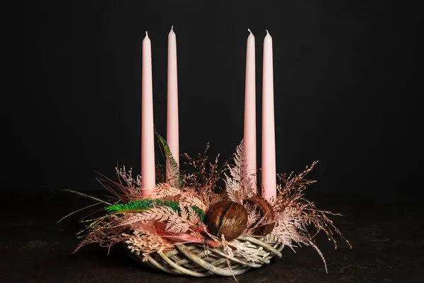Decorative wreath of four pink Advent candles in an Advent wreath decoration on a dark background in a floral style. Tradition before Christmas. Festive still life.
