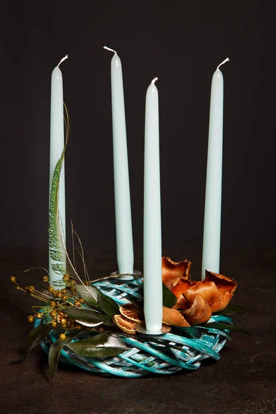 Symbolic Advent wreath with 4 candles Decorative wreath of four blue Advent candles in an Advent wreath decoration on a dark background. Tradition before Christmas. Festive still life.
