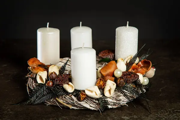Symbolic Advent wreath with 4 candles Decorative wreath of four white Advent candles in an Advent wreath decoration on a dark background. Tradition before Christmas. Festive still life.