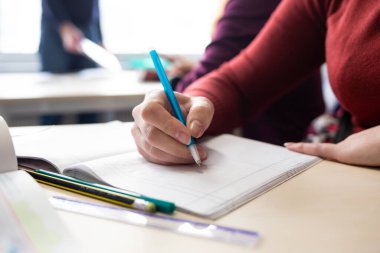 Masada otururken not defterine not yazan genç bir adamın yakın çekimi..