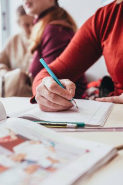 Masada oturmuş kitap çizen genç bir çiftin yakın çekimi.