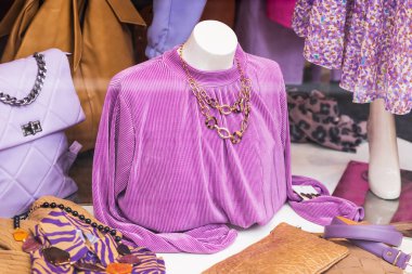 Ahşap bir pencerenin arkasında elbise ve etek giymiş bir manken.