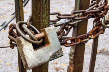 Üzerinde kilit olan paslı bir zincir. Kilit gümüş ve zincir paslanmış.                        