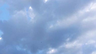 Kamera yerden göğe doğru süzülüyor, parlak ve parlak beyaz bulutları temiz mavi arkaplanda yakalıyor..