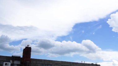 Kamera arazide yavaşça döner, yumuşak mavi bir gökyüzünün altında ağaçlar ve çatılar olan bir ufku yavaş yavaş ortaya çıkarır. Tam HD video.