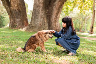 A girl sits with a brown dog in the garden.
