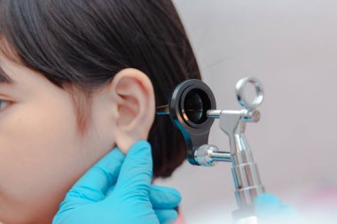 Bir doktor bir çocuğun kulaklarını incelemek için ostomokop kullanır..