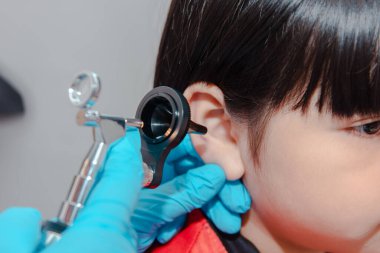 Bir doktor bir çocuğun kulaklarını incelemek için ostomokop kullanır..