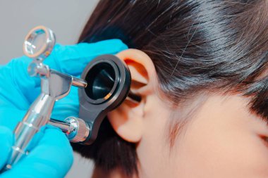 Bir doktor bir çocuğun kulaklarını incelemek için ostomokop kullanır..