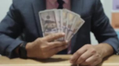 Banka veznedarı çalışıyor ve 100 dolar sayıyor.