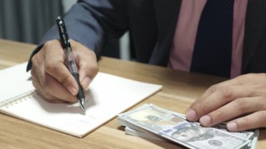 Banka veznedarı çalışıyor ve 100 dolar sayıyor.