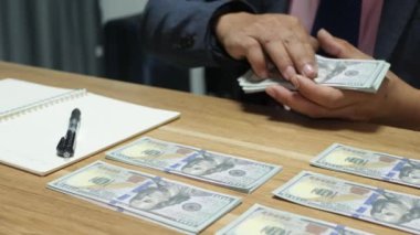 Banka veznedarı çalışıyor ve 100 dolar sayıyor.