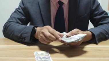 Banka veznedarı çalışıyor ve 100 dolar sayıyor.