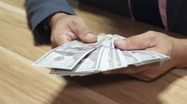 Banka veznedarı çalışıyor ve 100 dolar sayıyor.