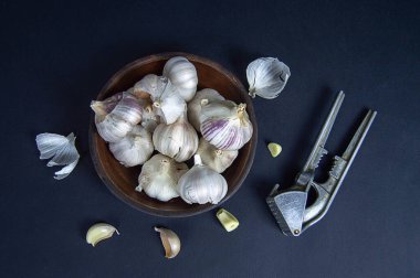 Sarımsak kafalar ve karanlığa gömülmüş bir kasede, eski bir sarımsak eziciyle.