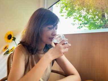 Kahve içen, mutlu bir şekilde gülümseyen bir kadın.,