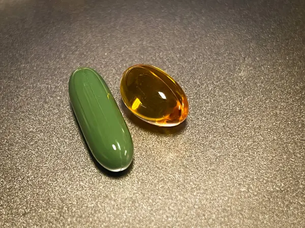 Soft gel capsule of vitamin put on background