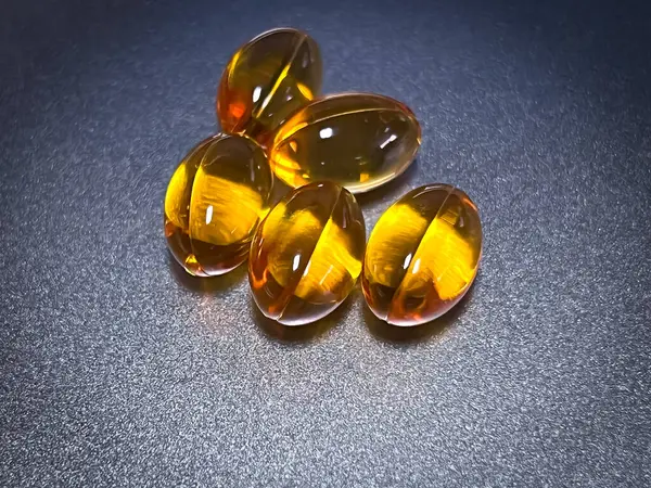 Soft gel capsule of vitamin put on background