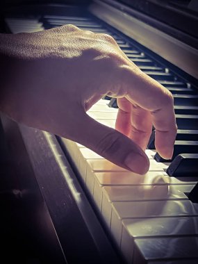 Piyanonun tuşlarına basan insan parmağı, klasik ton, bulanık ışık...
