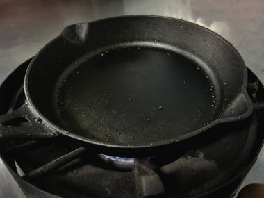 Ocağa demir tava dök, yağ spreyi ile ıslat, yemek pişirmeye hazırlan. Mutfak gereçleri, mutfak malzemeleri..