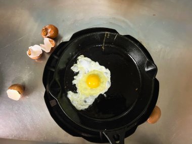 Siyah tavada tek yumurta, sobanın üstünde, geleneksel ev yapımı yemek pişirme tarzı..