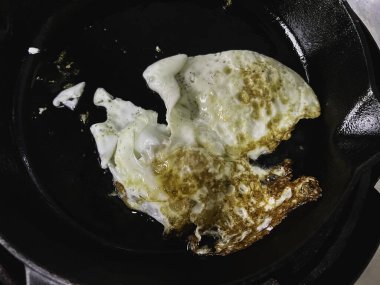 Siyah tavada yumurta sarısı, sobanın üstünde, geleneksel ev yapımı yemek pişirme tarzı..