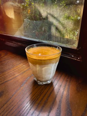 Sıcak kahve, bardakta soğuk süt, tahta tahta tahta, bulanık ışık..