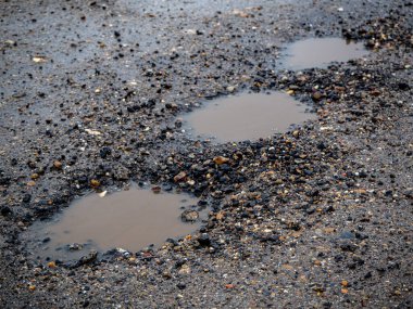 Yağmurlu bir kış gününde kaldırımlı bir yolda çukur. Risk ve trafik sorunları kavramı hd