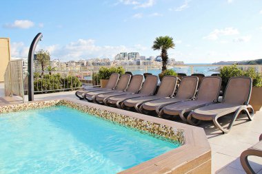 Gzira, Malta - December 20 2022: Hotel Resort with Rooftop Pool and Beach Chairs. Beautiful Panoramic View in Gzira, Malta clipart