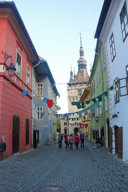 Sighisoara, Romanya - 27 Eylül 2019: Saat Kulesi ve Turistli Sighisoara Eski Kent Caddesi. Romanya 'daki Transilvanya Manzarası.