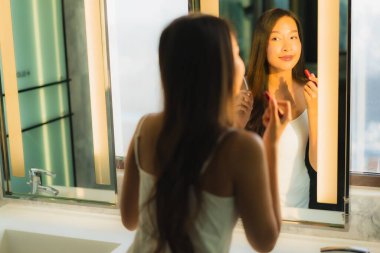 Güzel bir Asyalı kadın portresi makyaj malzemesi makyaj malzemesi ve yüz makyajı ile banyo içinde yüz maskesi.