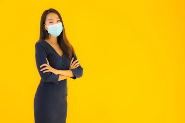 Koronavirüsten korunmak için maske takmış güzel Asyalı bir kadın portresi ve sarı izole edilmiş arka planda 19 numara.