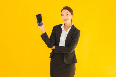 Portre güzel genç Asyalı kadın akıllı cep telefonu ve kahve fincanı ile izole edilmiş sarı arka planda