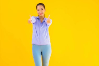 Sarı izole edilmiş arka planda spor giysili güzel Asyalı kadın portresi egzersize hazır.