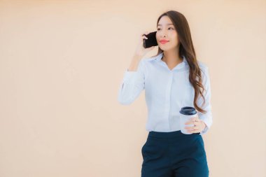 Akıllı cep telefonu ve kahve fincanı olan güzel bir iş kadını portresi.