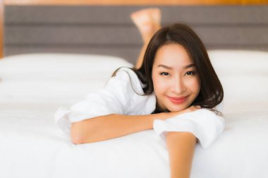Güzel bir Asyalı kadın portresi. Yatak odasında rahat bir gülümseme.