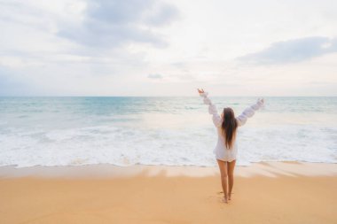 Güzel bir Asyalı kadın portresi deniz kenarında tatil yaparken rahatlar.