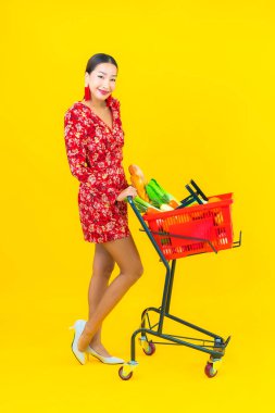 Sepetinde market sepeti ve market arabası olan güzel bir Asyalı kadın portresi.