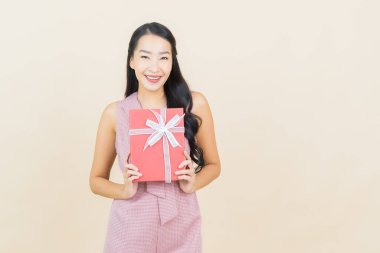 Güzel bir Asyalı kadının portresi. Arka planda kırmızı hediye kutusuyla gülümsüyor.
