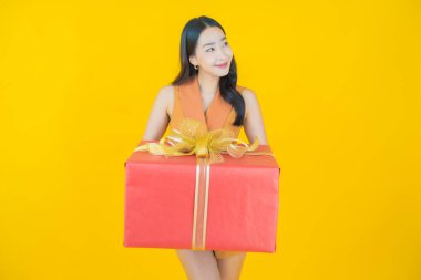 Güzel bir Asyalı kadının portresi. Arka planda kırmızı hediye kutusuyla gülümsüyor.