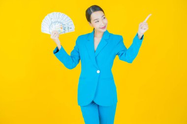 Asyalı güzel bir kadının portresi. Renkli arka planda bol para ve parayla gülümsüyor.