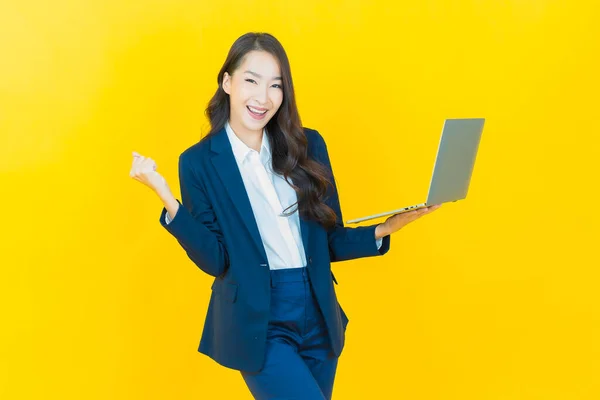 外型美丽的年轻亚洲女人带着电脑笔记本电脑在与世隔绝的背景下微笑 — 图库照片