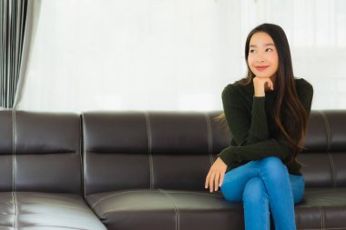 Güzel bir portre. Genç Asyalı kadın. Oturma odasındaki kanepede rahatla.
