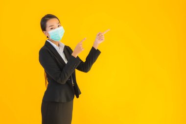 Güzel genç iş kadını portresi Korunmak için maske takıyor 19 koronavirüs sarı izole arka planda